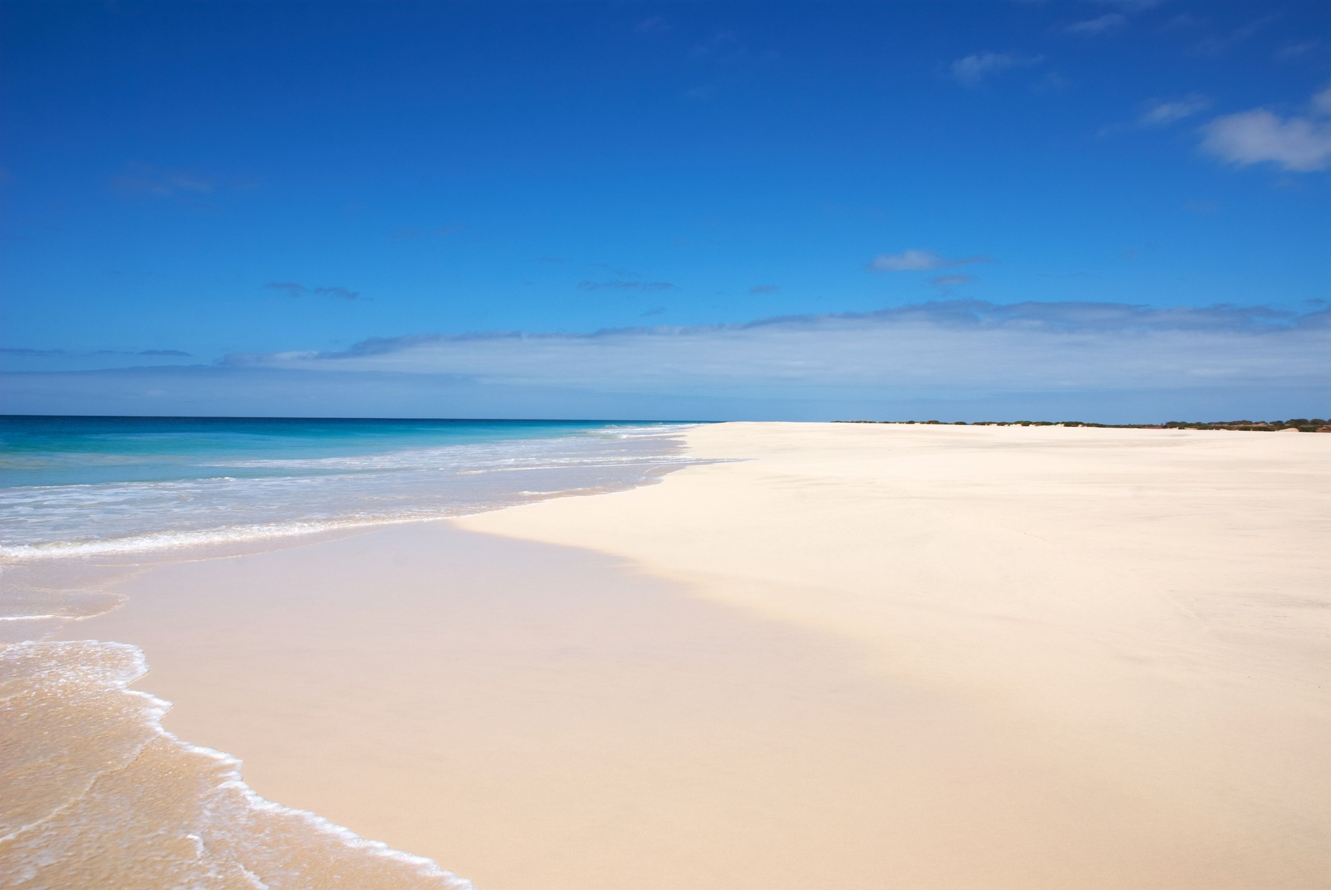 An endless stretch of pristine white sand meets the turquoise Atlantic Ocean at Santa Monica Beach, Boa Vista, Cape Verde.